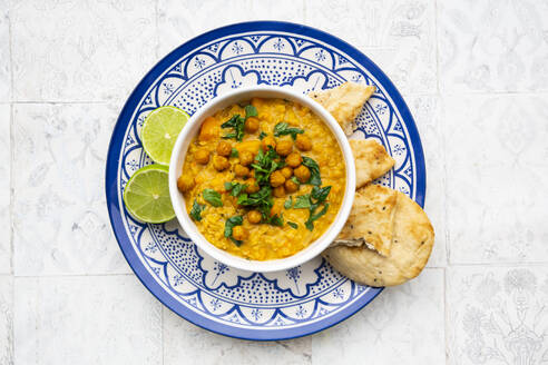 Vegan lentil curry with red lentils, sweet potatoes, spinach, roasted turmeric, chickpeas, with lime juice and coriander and naan bread - LVF08577