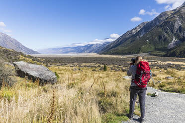 New Zealand, Oceania, South Island, Canterbury, Ben Ohau, Southern Alps (New Zealand Alps), Mount Cook National Park, Rear view of tourist photographing Tasman Valley - FOF11620