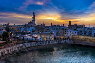 Italy, Apulia, Monopoli, Aerial view of sea and old town at sunset - AMF07786