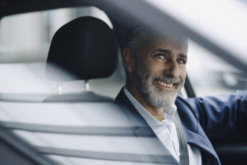 Porträt eines lächelnden reifen Geschäftsmannes in seinem Auto - KNSF07373