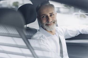 Portrait of smiling mature businessman in his car - KNSF07376