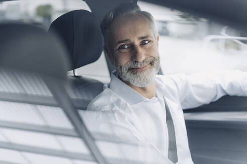 Porträt eines lächelnden reifen Geschäftsmannes in seinem Auto - KNSF07376