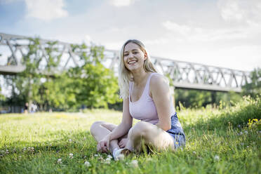 Porträt einer glücklichen jungen Frau, die sich im Sommer auf einer Wiese entspannt, Berlin, Deutschland - BFRF02178