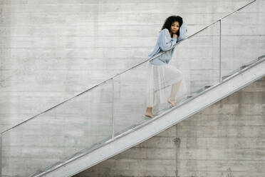 Beautiful young woman standing on stairs outdoors - TCEF00095