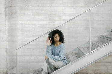 Schöne junge Frau sitzt auf einer Treppe hinter einer Glasscheibe - TCEF00099