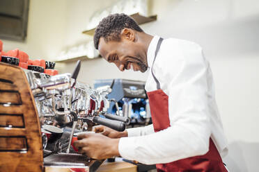 Lächelnde Barista bei der Zubereitung eines Kaffees in einem Café - OCMF01024