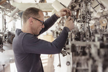 Mann arbeitet an einer Maschine in einer Textilfabrik - SDAHF00056
