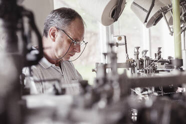 Mann arbeitet an einer Maschine in einer Textilfabrik - SDAHF00059