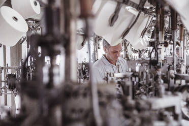 Mann arbeitet an einer Maschine in einer Textilfabrik - SDAHF00068