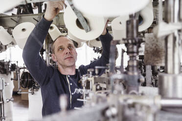 Mann arbeitet an einer Maschine in einer Textilfabrik - SDAHF00071