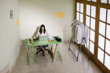 Junge Frau mit Laptop auf dem Schreibtisch im Büro - JRFF04038
