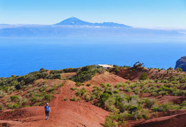 Spanien, Kanarische Inseln, Agulo, Weibliche Rucksacktouristin auf dem Weg zum Aussichtspunkt Mirador de Abrante mit dem Berg Teide in der Ferne - SIEF09485