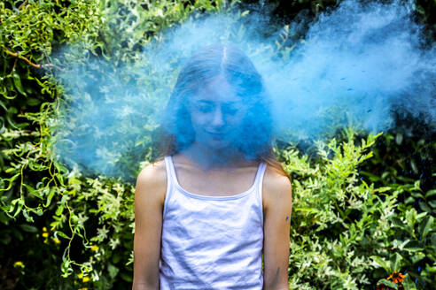 Portrait of girl behind blue powder paint cloud - SARF04456