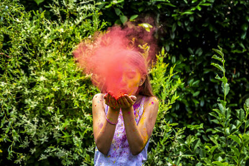 Girl blowing red powder paint in nature - SARF04457
