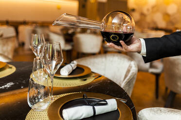 Kellner gießt in einem schicken Restaurant Wein aus einer Karaffe in ein Glas - VABF02574
