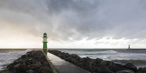 Deutschland, Mecklenburg-Vorpommern, Warnemünde, Sturmwolken über Seebrücke und Leuchtturm - WDF05719