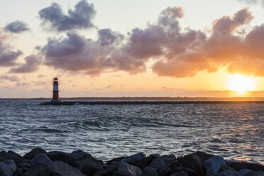 Germany, Mecklenburg-West Pomerania, Warnemunde, Lighthouse and sea at sunset - WDF05725