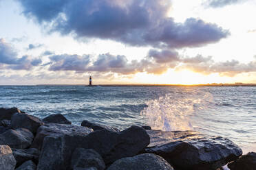 Germany, Mecklenburg-West Pomerania, Warnemunde, Lighthouse and sea at sunset - WDF05726
