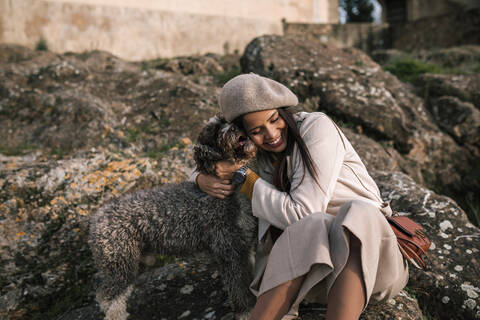 Glückliche junge Frau, die ihren Hund in der Stadt knuddelt, lizenzfreies Stockfoto