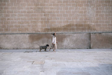 Junge Frau beim Spaziergang mit ihrem Hund in der Stadt - GRCF00153