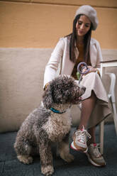 Young woman sitting with her dog in a cafe in the city - GRCF00155