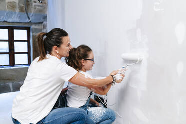 Mutter und Tochter streichen gemeinsam eine Wand in ihrem neuen Haus - DGOF00220