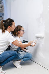 Mutter und Tochter streichen gemeinsam eine Wand in ihrem neuen Haus - DGOF00221