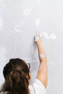 Mädchen malt mit dem Finger auf eine Wand - DGOF00224