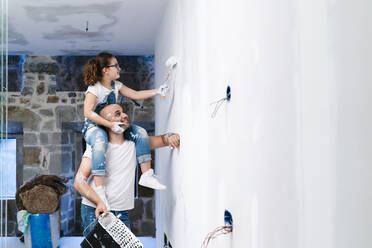 Mädchen sitzt auf den Schultern des Vaters und streicht die Wand ihres neuen Hauses - DGOF00232
