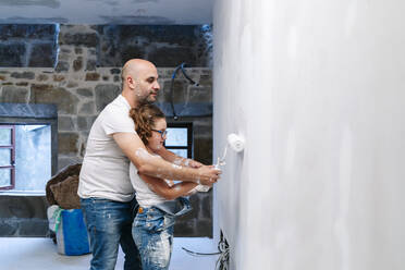 Vater und Tochter streichen gemeinsam eine Wand in ihrem neuen Haus - DGOF00239