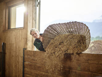 Bäuerin schüttet Stroh in die Scheune auf einem Bauernhof - CVF01562