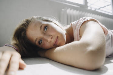 Portrait of beautiful blond young woman lying on the floor - KNSF07383