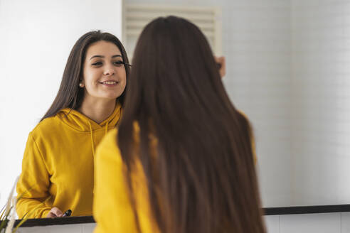 Spiegelbild eines Teenagers, der Wimperntusche aufträgt - DLTSF00430