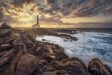 Spain, Menorca, Rocky coast and Favaritx lightouse at sunset - DVGF00078