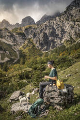 Frau mit Hund auf Wandertour am Wilden Kaiser beim Pausieren, Kaisergebirge, Tirol, Österreich - MSUF00170