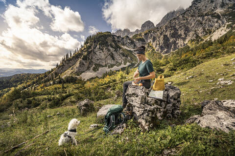 Frau mit Hund auf Wandertour am Wilden Kaiser beim Pausieren, Kaisergebirge, Tirol, Österreich, lizenzfreies Stockfoto