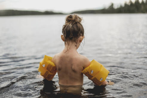 Girl wearing armbands in lake - JOHF06253