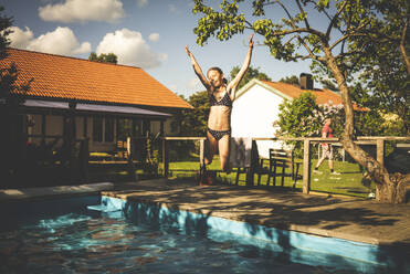 Girl jumping into swimming-pool - JOHF06260