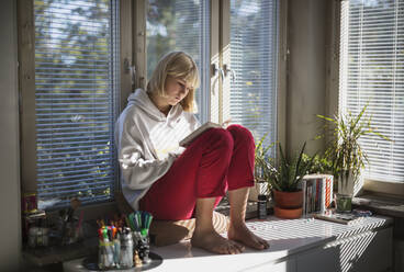 Teenager-Mädchen sitzt auf dem Schreibtisch - JOHF06339