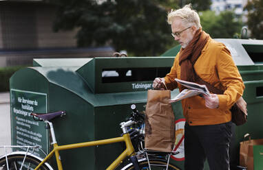 Mann wirft Müll in die Recycling-Tonne - JOHF06342