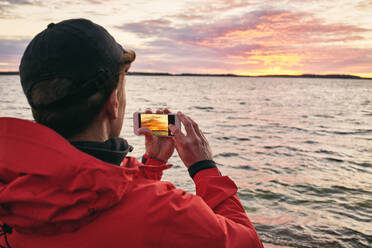 Mann beim Fotografieren des Sonnenuntergangs - JOHF06419