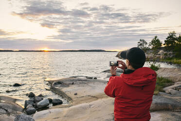 Mann beim Fotografieren des Sonnenuntergangs - JOHF06421