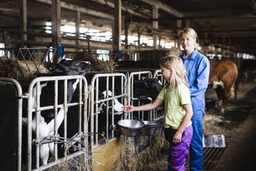 Woman and daughter in cowshed - JOHF06439