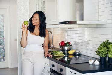 Lächelnde Frau mit Apfel in der Hand - JOHF06602