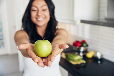 Lächelnde Frau mit Apfel in der Hand - JOHF06604