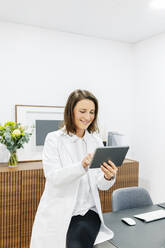 Smiling doctor using tablet in her medical practice - DGOF00259