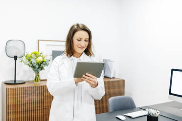 Lächelnde Ärztin mit Tablet in ihrer Praxis - DGOF00260