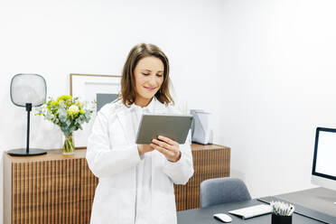 Smiling doctor using tablet in her medical practice - DGOF00260