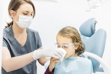 Mädchen beim Zahnarzt, das sich den Mund wäscht - DGOF00274