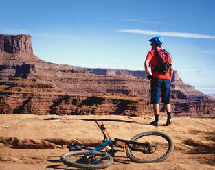 Anonymous cyclist admiring canyon on sunny day - CAVF73674